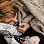 A woman wrapped in a blanket receiving medication while resting at home.
