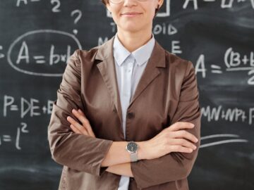 Portrait of a teacher standing in front of a blackboard full of mathematical equations.