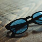 High angle trendy sunglasses with blue glass and black frames placed on wooden table