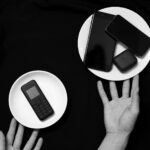 Contrasting old and new phones on plates in a minimalist black and white setup.