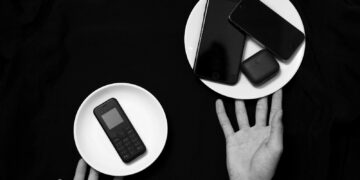 Contrasting old and new phones on plates in a minimalist black and white setup.