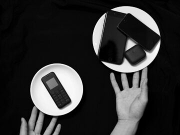 Contrasting old and new phones on plates in a minimalist black and white setup.