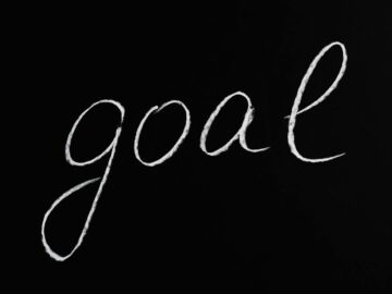 Elegant handwritten 'goal' on a black chalkboard background conveying ambition and purpose.