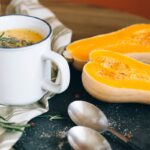 Cozy and warm butternut squash soup with sliced squash and fresh herbs.