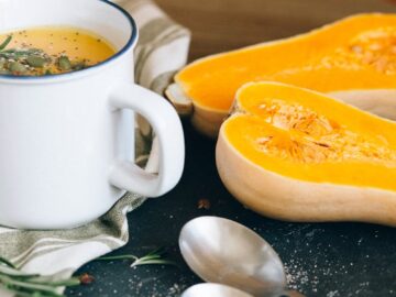 Cozy and warm butternut squash soup with sliced squash and fresh herbs.