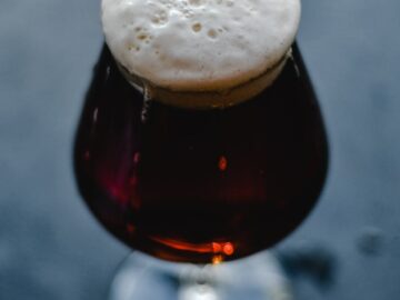 A close-up of a dark beer in a glass with a frothy head, showcasing the rich texture and color.