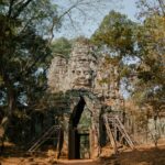 Historic stone entrance gate of Angkor Thom in Cambodia surrounded by lush greenery.