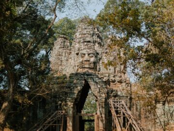 Historic stone entrance gate of Angkor Thom in Cambodia surrounded by lush greenery.
