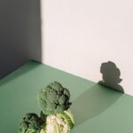 Broccoli and cauliflower with shadows on a green surface, captured in natural light.