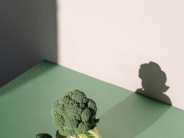 Broccoli and cauliflower with shadows on a green surface, captured in natural light.
