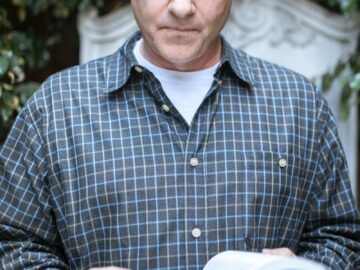 An adult man reads a Bible outdoors, exuding peace and contemplation in a serene setting.