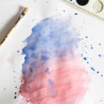 Vibrant watercolor painting with blue and red gradient, brush, and palette.
