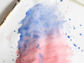 Vibrant watercolor painting with blue and red gradient, brush, and palette.