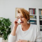 Woman crying over financial problems, surrounded by money indoors.
