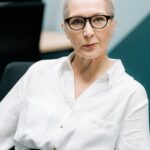 Stylish senior woman in glasses showcasing confidence in a professional office environment.