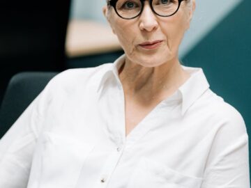 Stylish senior woman in glasses showcasing confidence in a professional office environment.