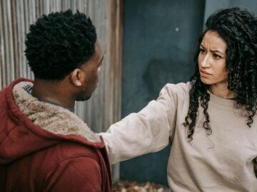 A diverse couple engages in a tense confrontation on an urban street.