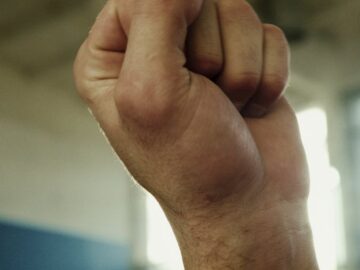 Vertical close-up of two fists raised symbolizing strength and unity.