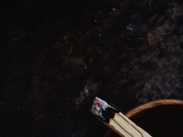 A close-up view of a burning Palo Santo stick resting in a wooden bowl; perfect for relaxation themes.