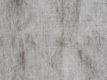 A textured and vintage linen fabric surface with natural wrinkles and neutral tones.