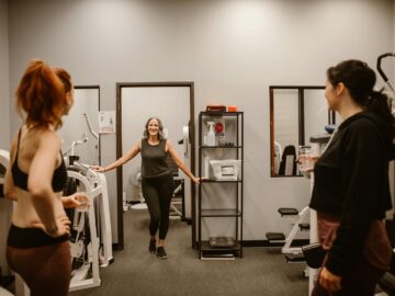 Three women in a gym setting focus on fitness and wellness after midlife.