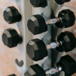 Close-up of black dumbbells on a rack in a contemporary gym with a brick wall backdrop.