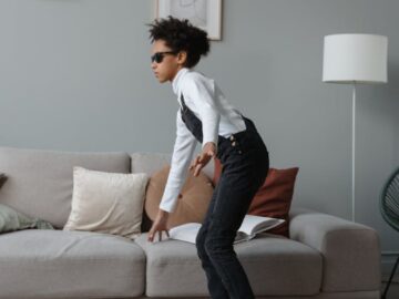 A young child with sunglasses in a contemporary living room, showcasing style and personality.