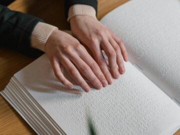 Close-up of hands reading Braille, symbolizing independence and accessibility for the visually impaired.