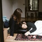 A woman comforts another during an emotional moment indoors, evoking themes of empathy and support.