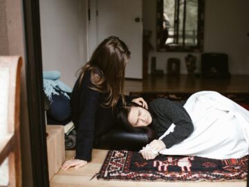 A woman comforts another during an emotional moment indoors, evoking themes of empathy and support.