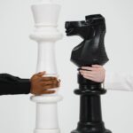 Two hands holding giant chess pieces representing strategic thinking and competition.