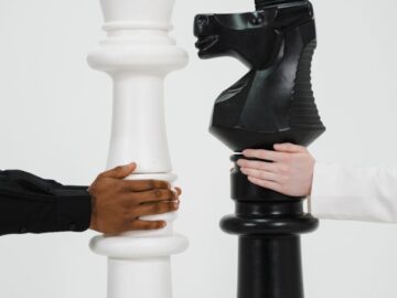 Two hands holding giant chess pieces representing strategic thinking and competition.