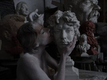 Creative sculptor in a cluttered studio with various busts.