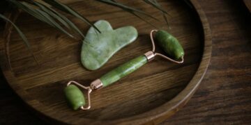 Close-up of jade roller and gua sha set elegantly displayed on a wooden tray with a natural aesthetic.