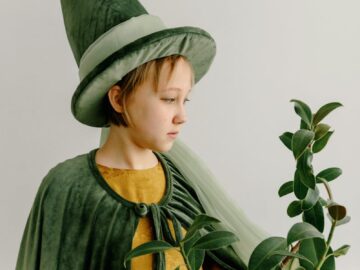 A child dressed as a wizard holding a plant, evoking fantasy and magic.