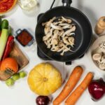 Top view of fresh vegetables, mushrooms, and kitchen ingredients on a white background, great for cooking and healthy eating themes.