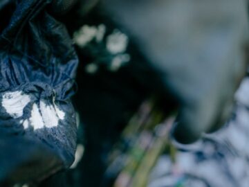 Close-up of swirling tie-dye fabric with blurred, artistic effect and water reflections.