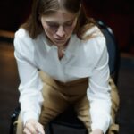 Focused young woman rehearsing her acting role on a stage, reading a script.