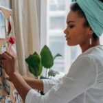 Woman creating a vision board with images in a stylish home setting, showcasing creativity and focus.