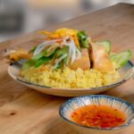 Tantalizing chicken and rice dish with fresh vegetables, served with a spicy dipping sauce.