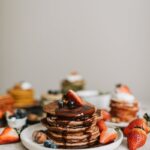 Stack of chocolate pancakes topped with fresh strawberries and blueberries, perfect for breakfast.