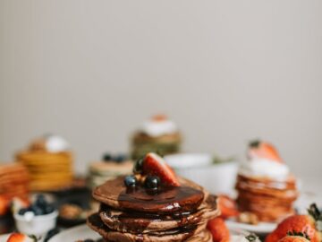 Stack of chocolate pancakes topped with fresh strawberries and blueberries, perfect for breakfast.