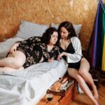 Two women enjoying a relaxed morning in a cozy bedroom setting, embracing comfort and connection.