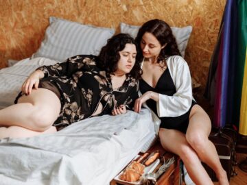 Two women enjoying a relaxed morning in a cozy bedroom setting, embracing comfort and connection.