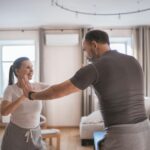 Senior couple engaging in fun exercises together at home, promoting fitness and bonding.