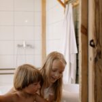 Two children having fun beside a sink in a cozy bathroom setting.