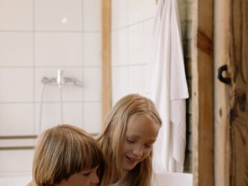 Two children having fun beside a sink in a cozy bathroom setting.