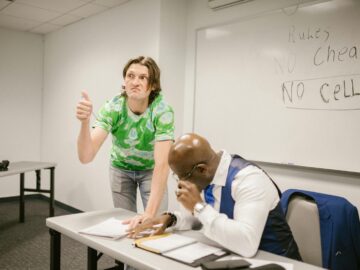 A teacher catches a student attempting to cheat with a hand signal during a classroom exam.