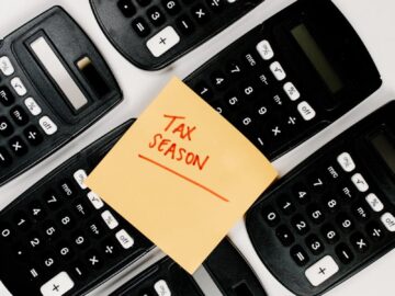 Top view of black calculators arranged around 'Tax Season' sticky note, perfect for finance concepts.