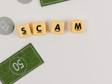 A minimal flat lay of a scam concept using dice and fake currency on a gray surface.